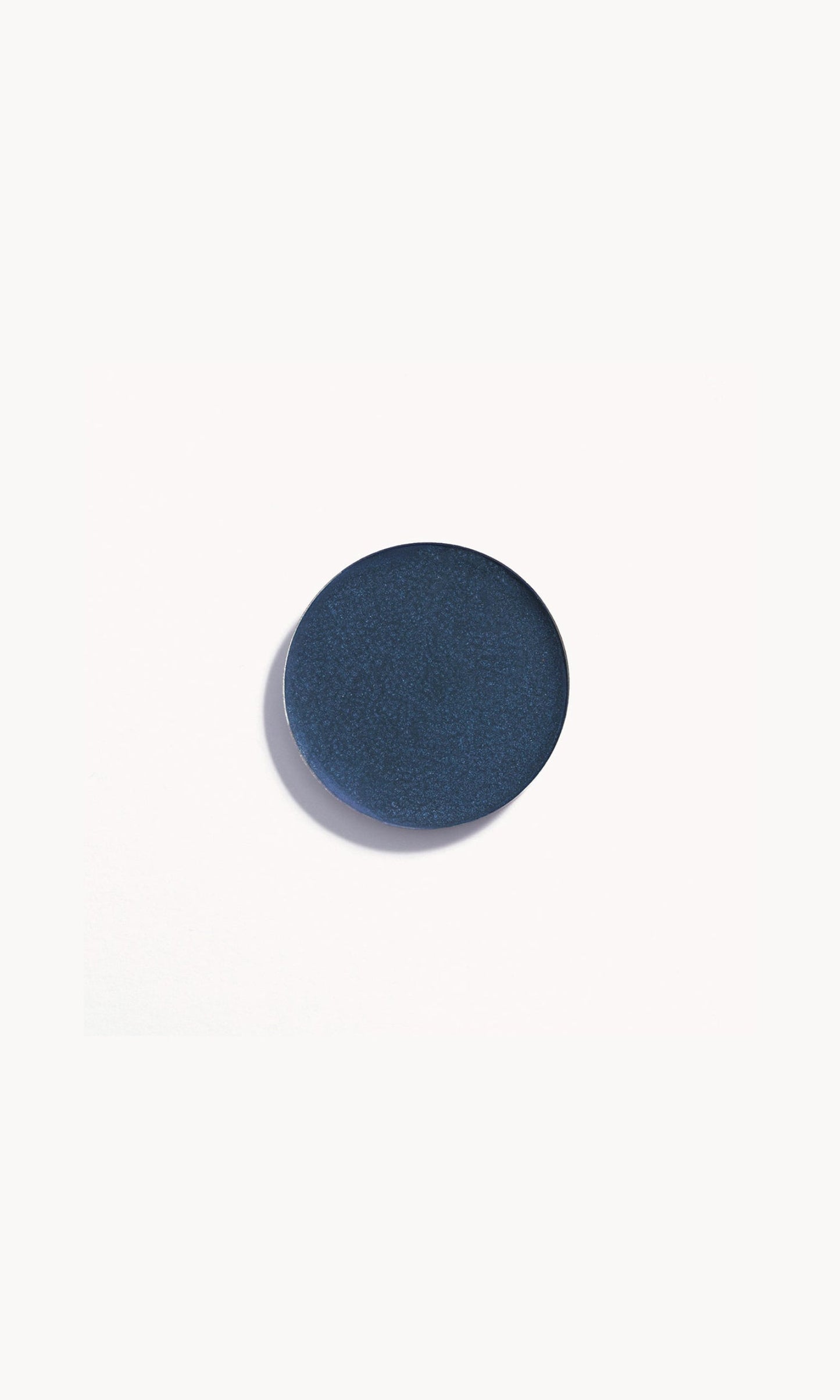 Circle of deep blue cream eye shadow on white background