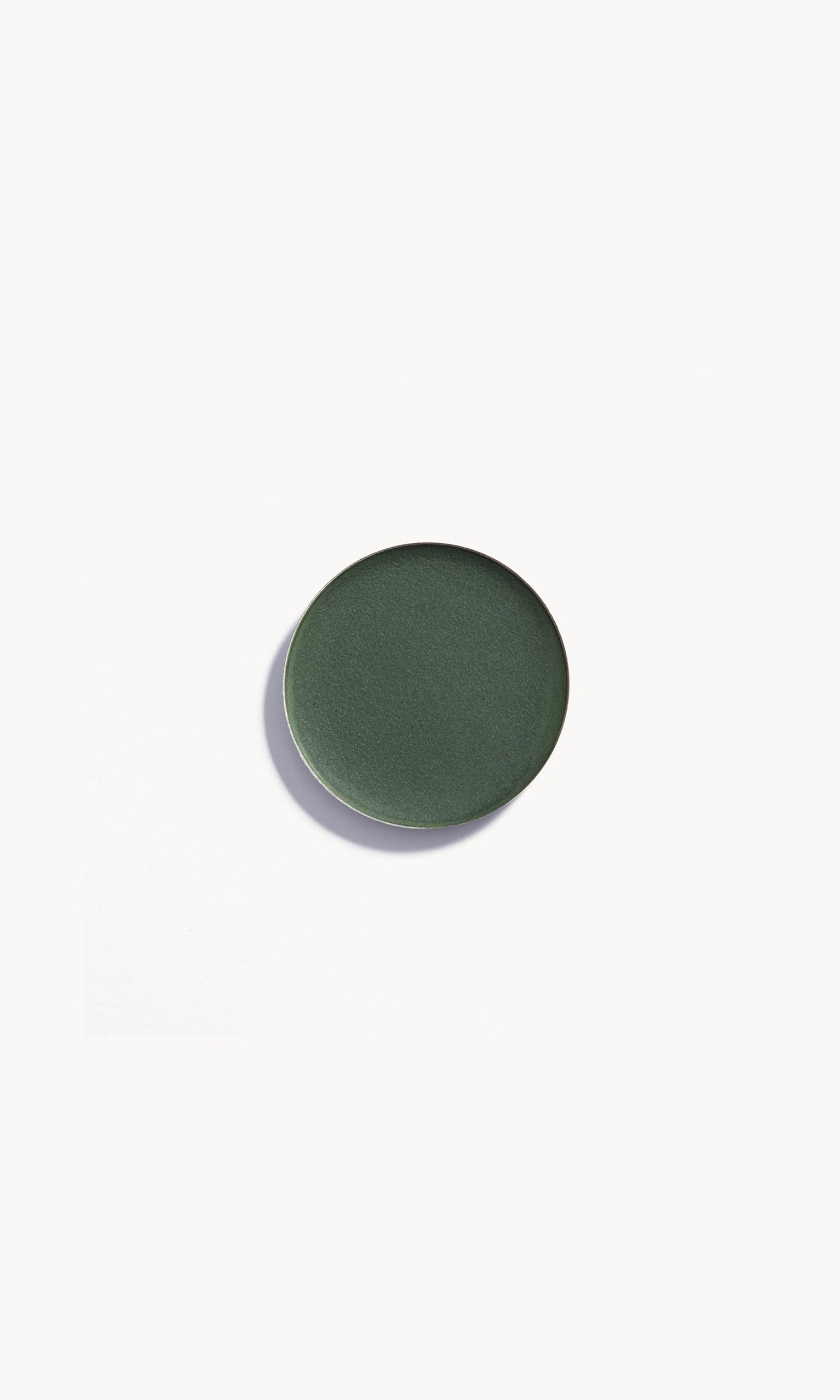 Circle of dark green cream eye shadow on white background
